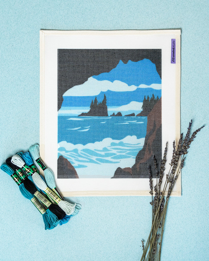 Needlepoint kit with a mountain and ocean design on a light blue background