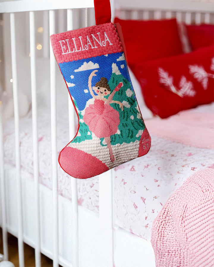 Christmas stocking with a ballerina design and 'Elliana' name, hanging on a crib.