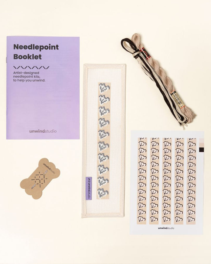 flat view of the Clay Leaf Key Fob Needlepoint Kit with printed canvas, matching threads, a instructional booklet and a graphic flyer
