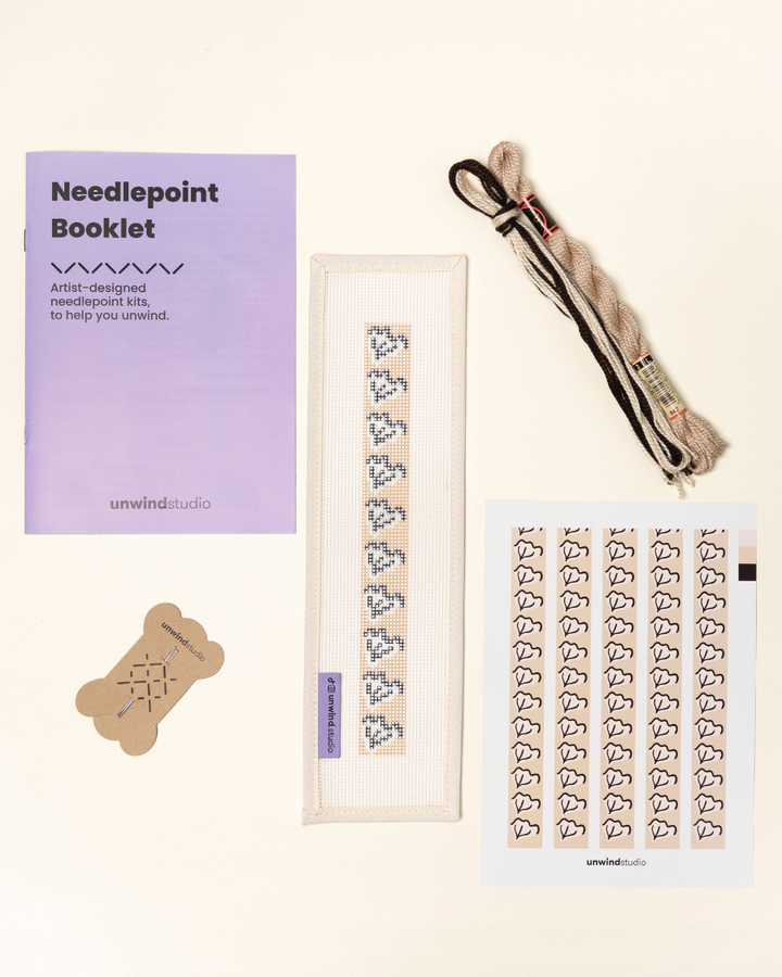 flat view of the Clay Leaf Key Fob Needlepoint Kit with printed canvas, matching threads, a instructional booklet and a graphic flyer
