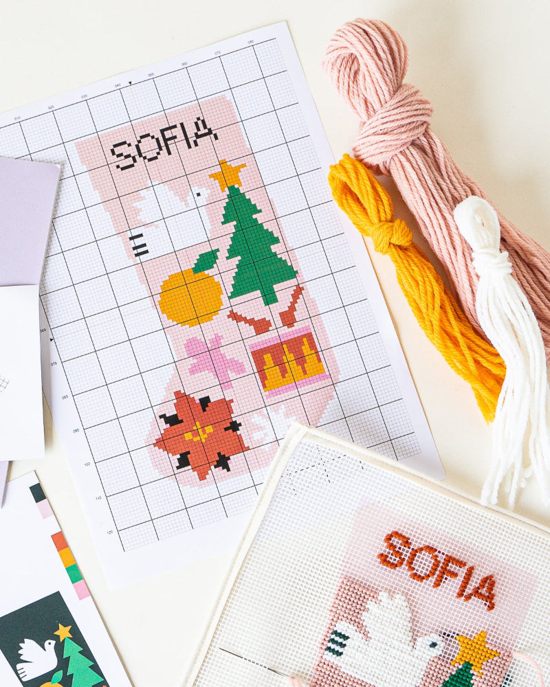 Cross-stitch patterns with 'Sofia' and festive designs, along with colorful threads on a white background.