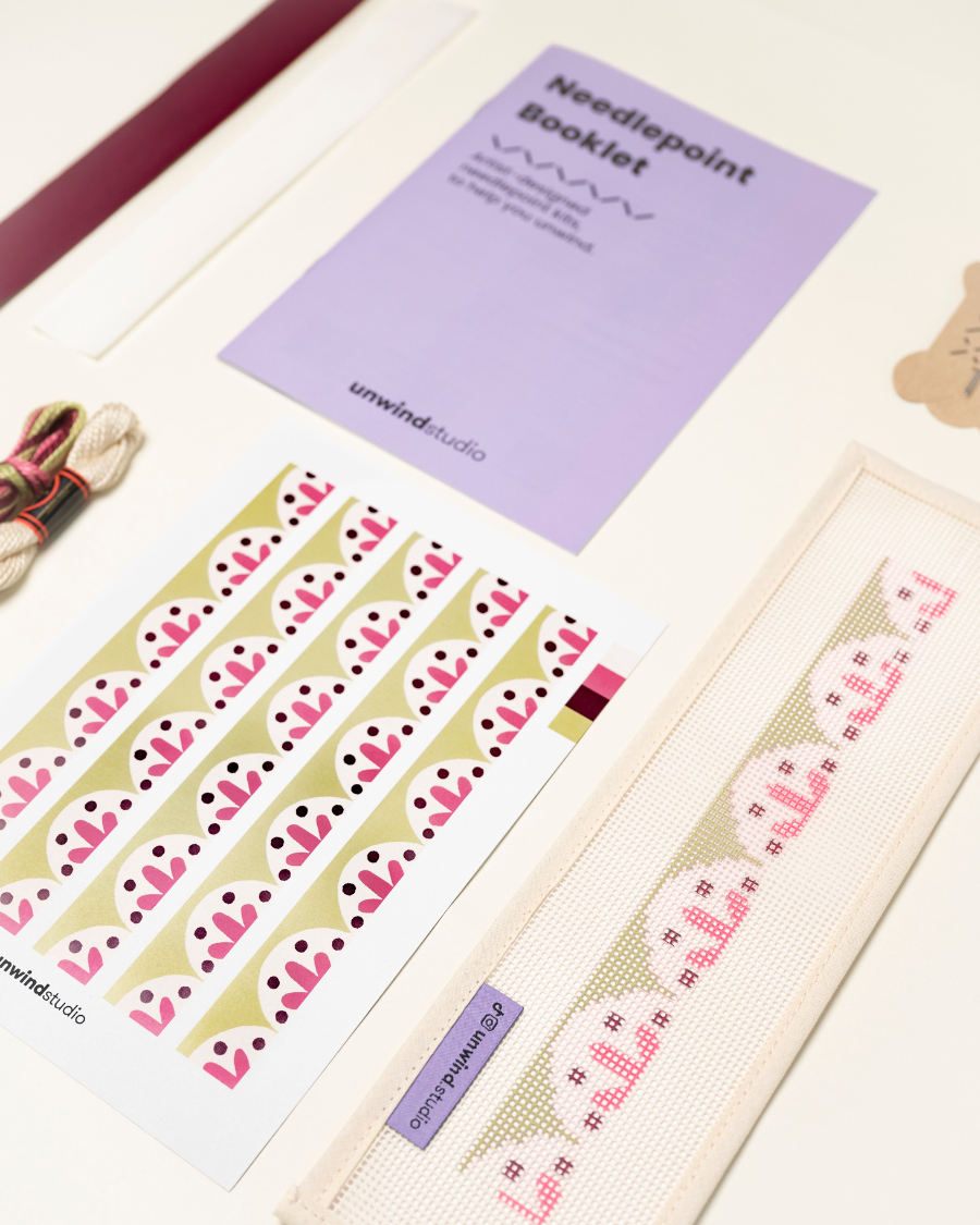 diagonal view of the Flourish Key Fob Needlepoint Kit with printed canvas, matching threads and finishing materials and a instructional booklet