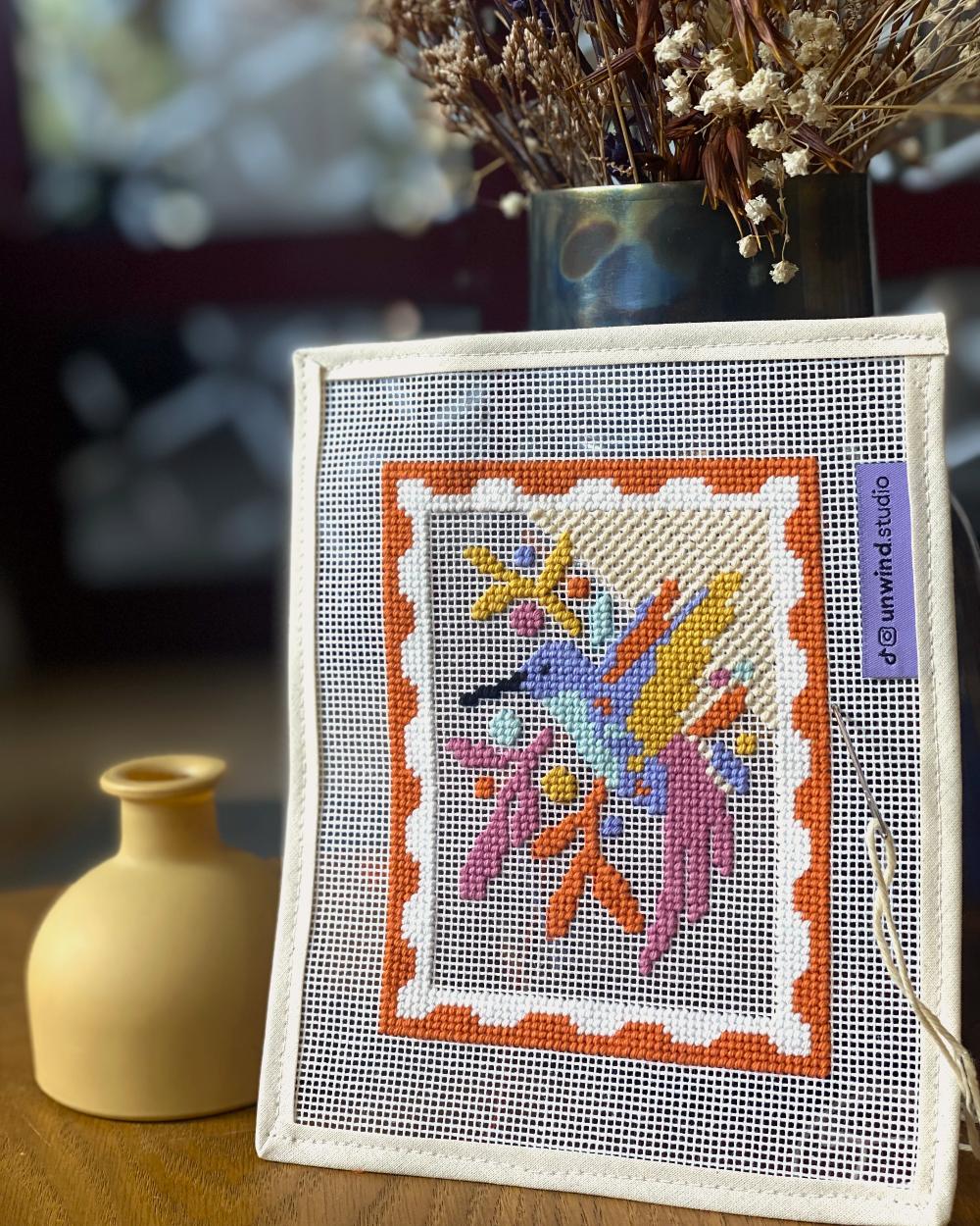 Hummingbird needlepoint canvas styled on wooden table.