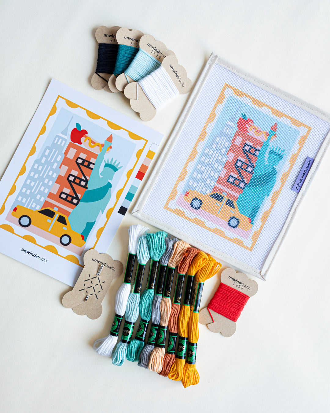 New York Stamp Needepoint Kit viewed diagonally with matching threads and flyer.