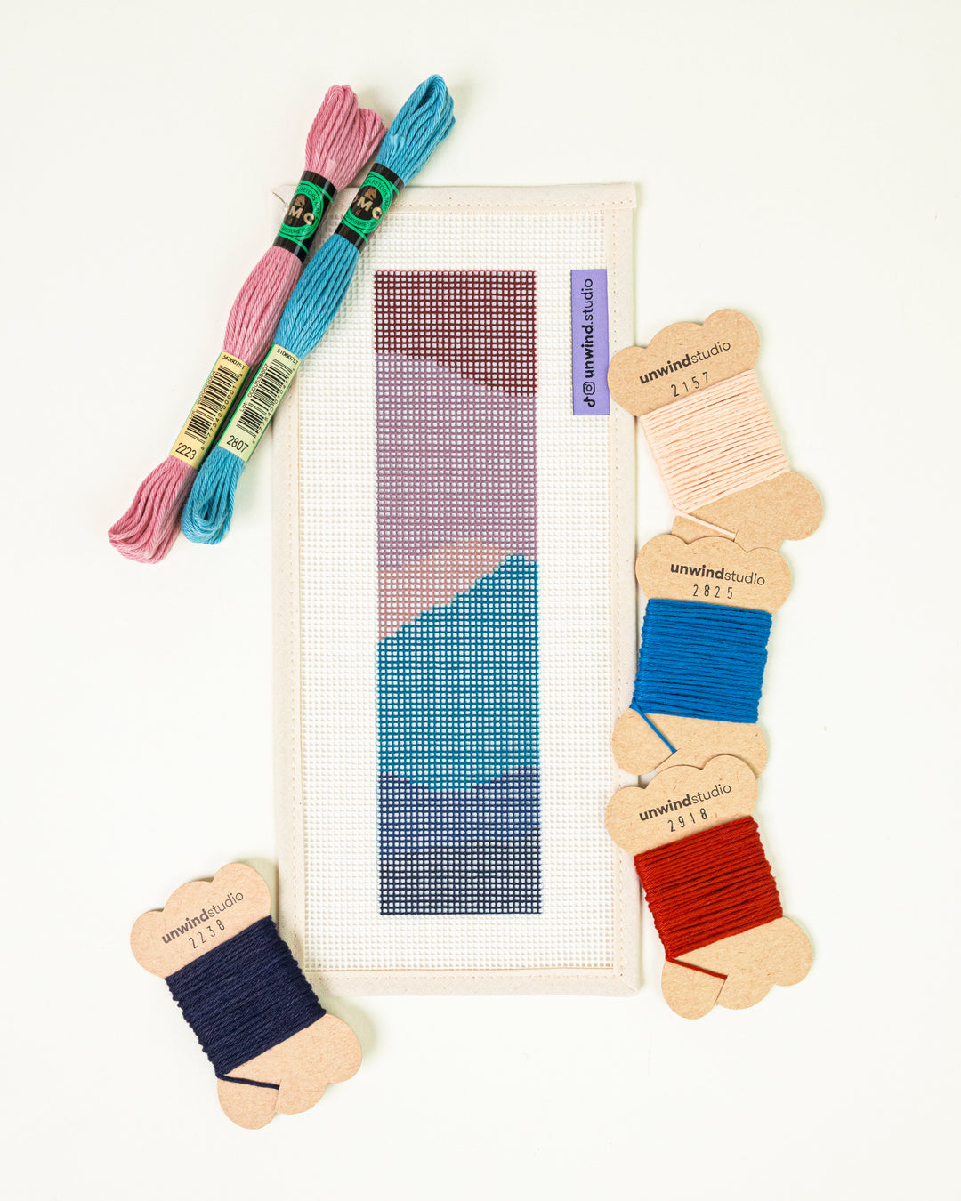 The Nightfall Mountains needlepoint bookmark kit with a colorfull mountain  design, surrounded by kit DMC Soft Cotton Threads.