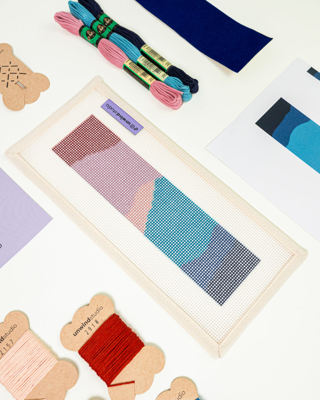 Close-up, diagonal view of the Nightfall Mountains needlepoint canvas and materials, showcasing the bold color palette and high-quality needlework supplies.