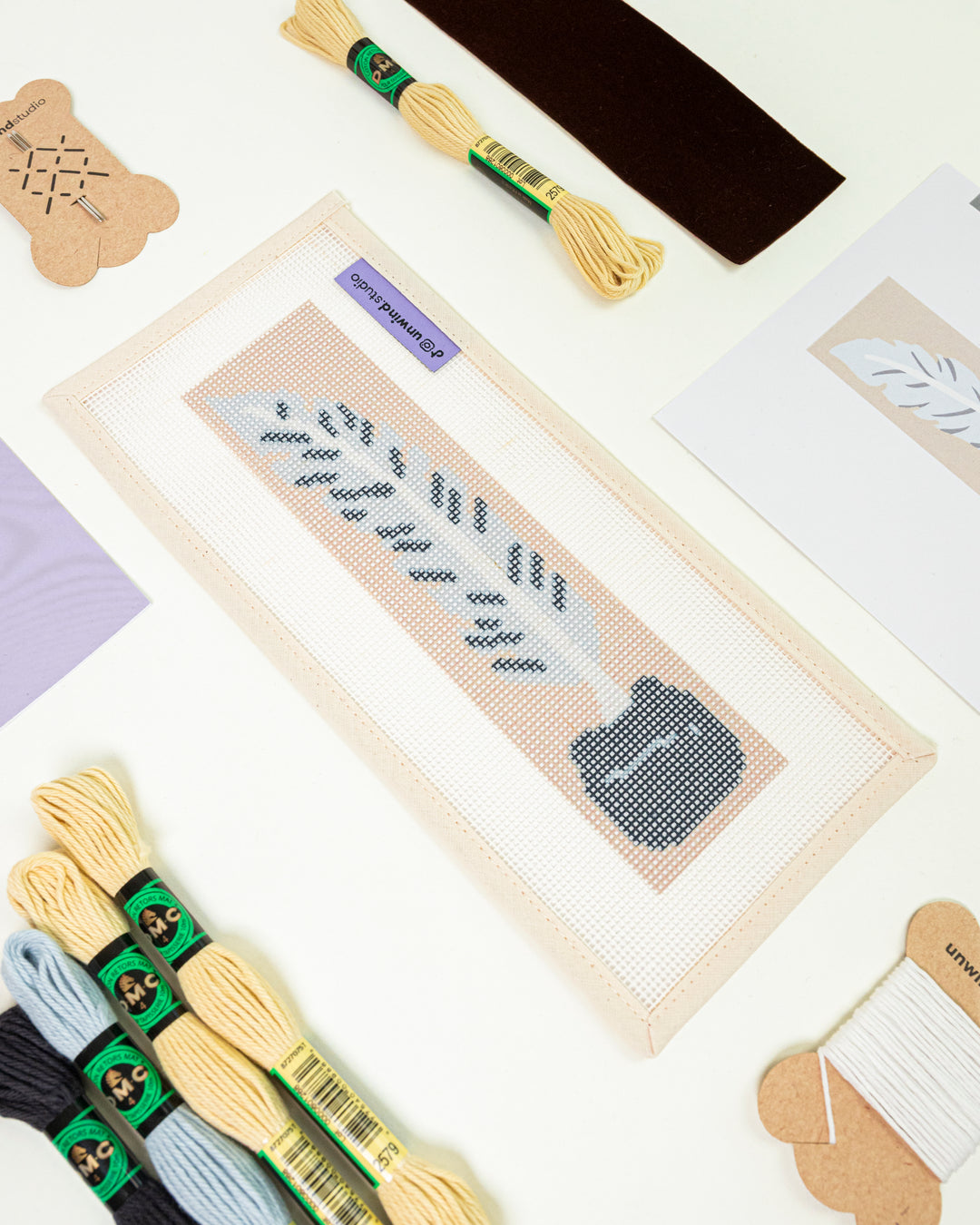 Close-up, diagonal view of the Quill Pen needlepoint canvas and materials, showcasing the soft pastel color palette and high-quality needlework supplies.