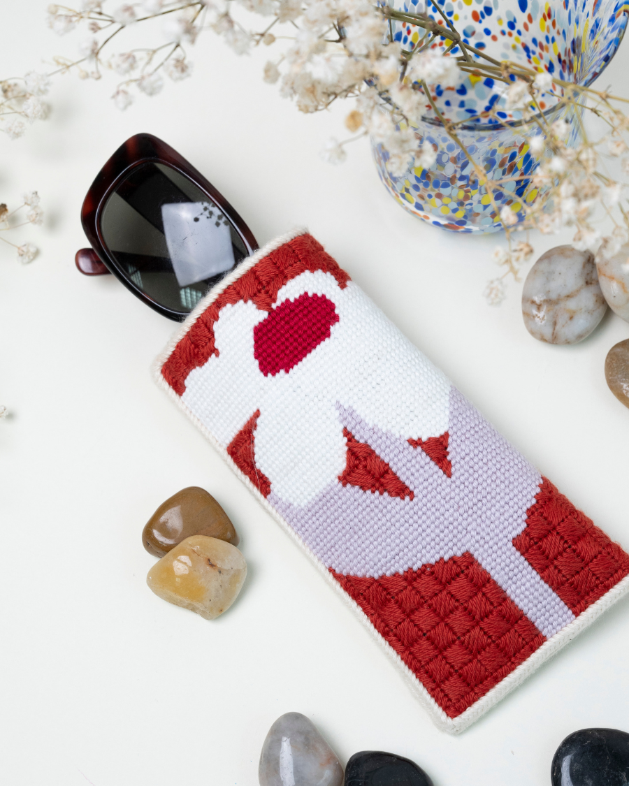 Sunny Sunday Sunglasses Needlepoint Kit by Unwind Studio with sunglasses placed inside of it and other decorative elements.