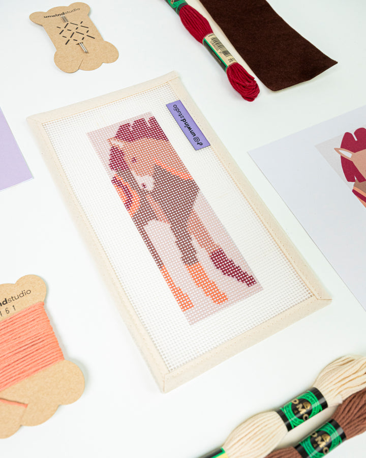 Close-up, diagonal view of The Horse Spirit needlepoint canvas and materials, showcasing the bold color palette and high-quality needlework supplies.
