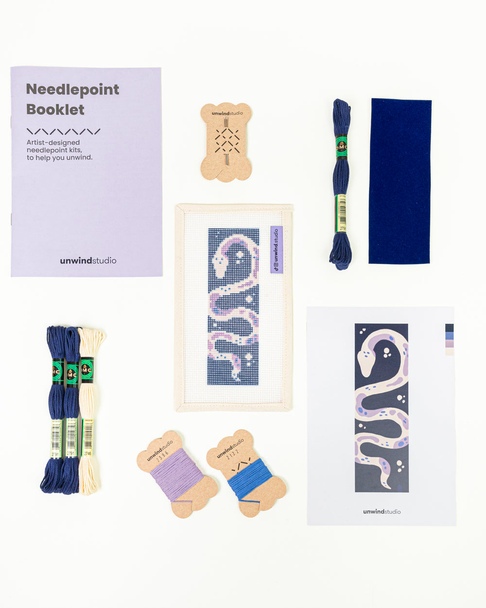 The Serpent's Tale needlepoint bookmark kit with a serpent design on a deep blue background, surrounded by kit DMC Soft Cotton Threads.