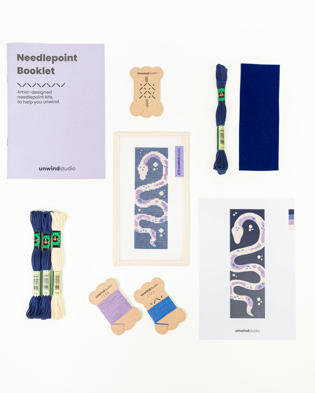 The Serpent's Tale needlepoint bookmark kit with a serpent design on a deep blue background, surrounded by kit DMC Soft Cotton Threads.