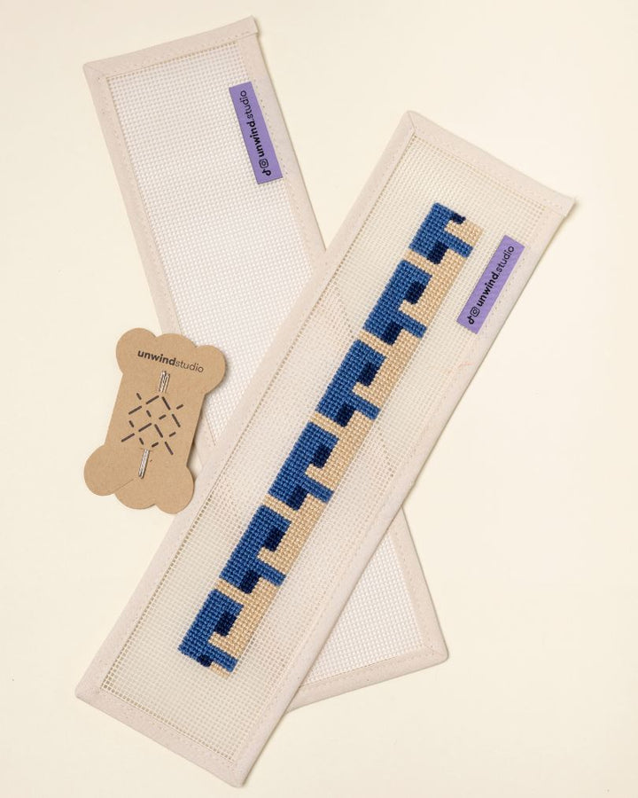 flat view of the Batik Key Fob Needlepoint Kit with blank canvas, a finished canvas and a pair of needles
