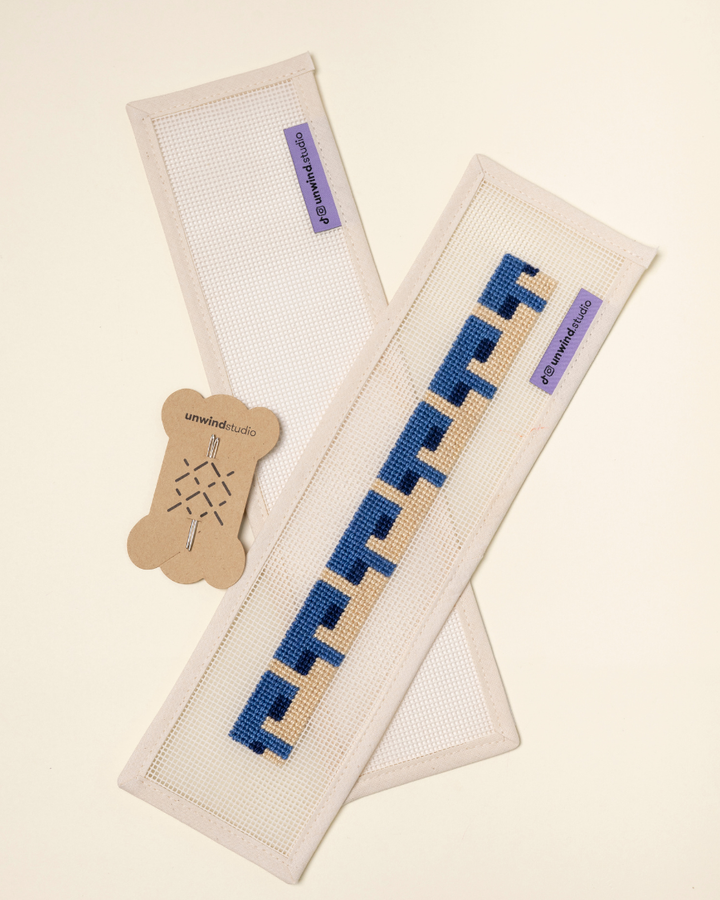 flat view of the Batik Key Fob Needlepoint Kit with blank canvas, a finished canvas and a pair of needles