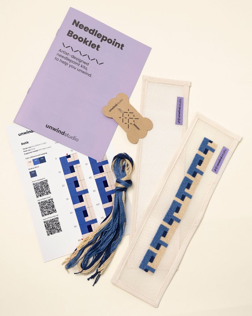 flat view of the Batik Key Fob Needlepoint Kit with blank canvas, matching threads, a instructional booklet and a graphic flyer
