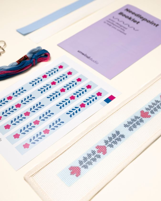 diagonal view of the Berry Vine Key Fob Needlepoint Kit with printed canvas, matching threads and finishing materials and a instructional booklet

