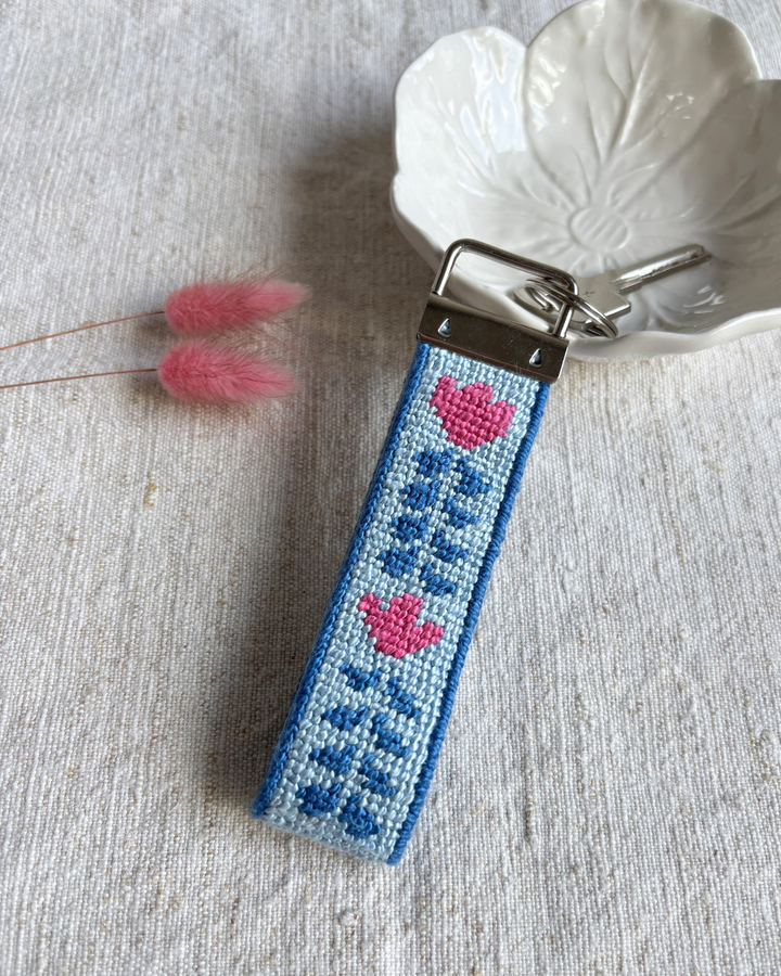 Berry Vine Key Fob Needlepoint Kit placed on top of a bowl with a dry flower on its side