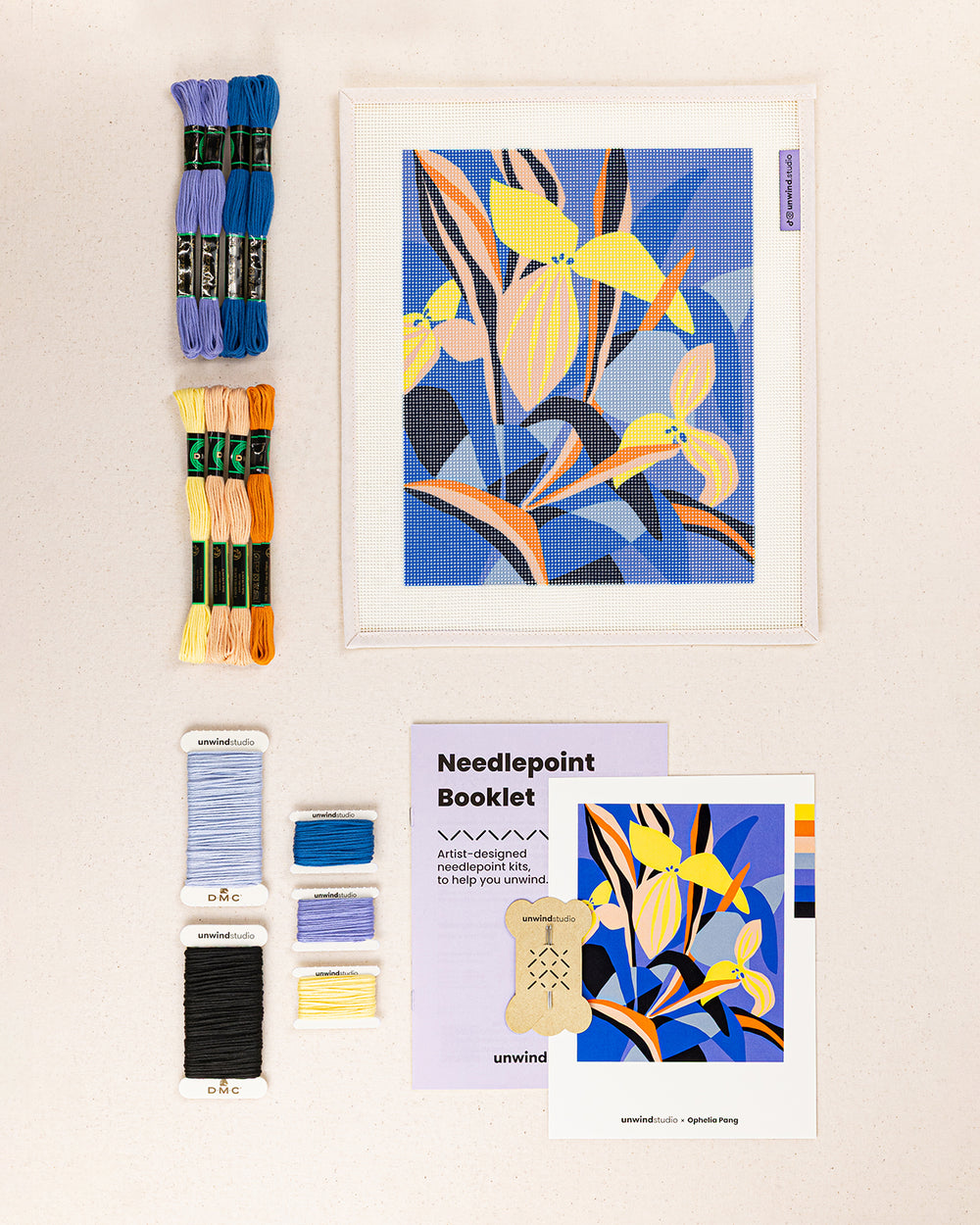 Blue Delight needlepoint kit contents: printed canvas, threads, needles, and instruction booklet, graphic flyer laid flat