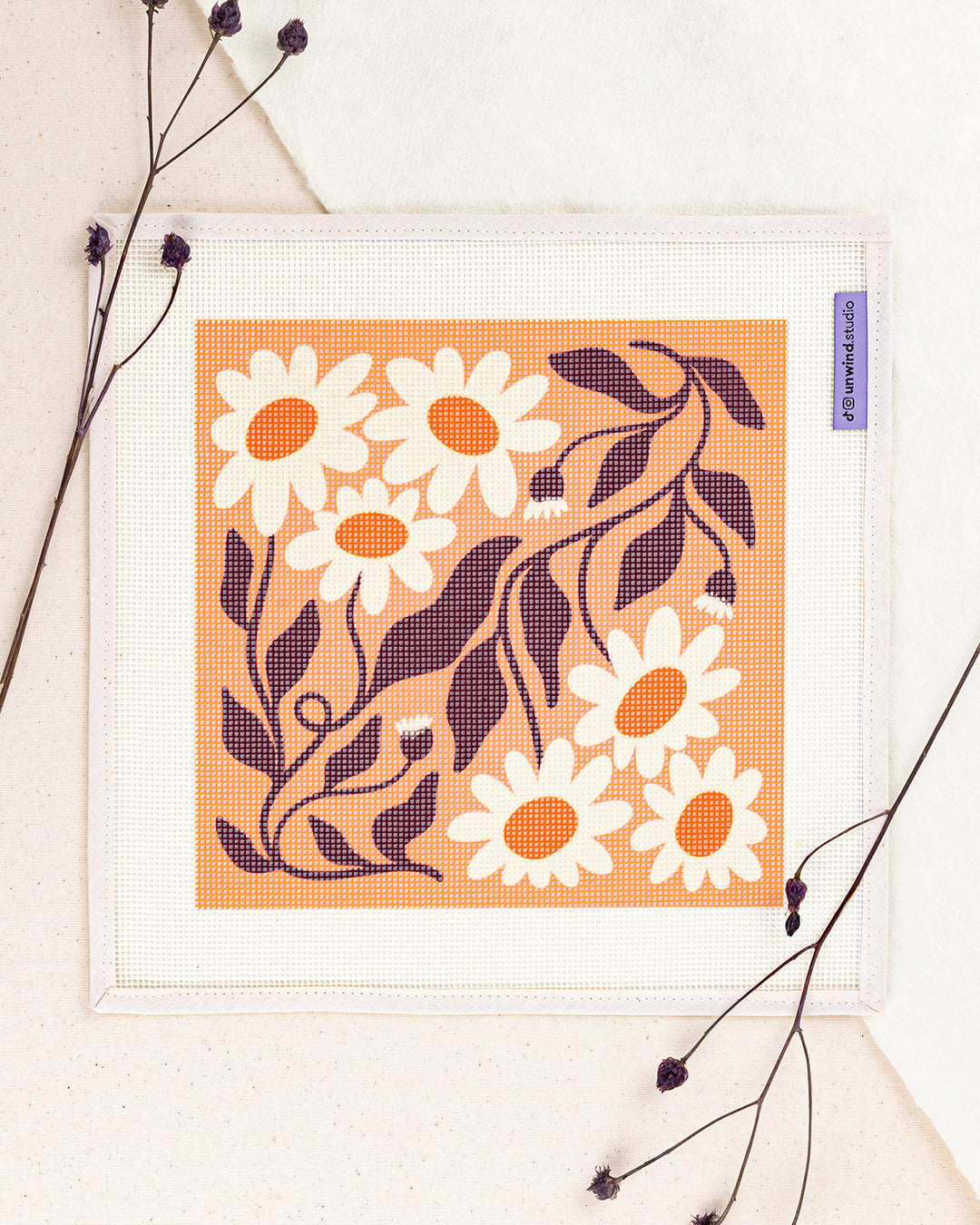 Daisy Chains needlepoint kit by Ophelia Pang: printed canvas of flowers on orange, framed with dried twigs