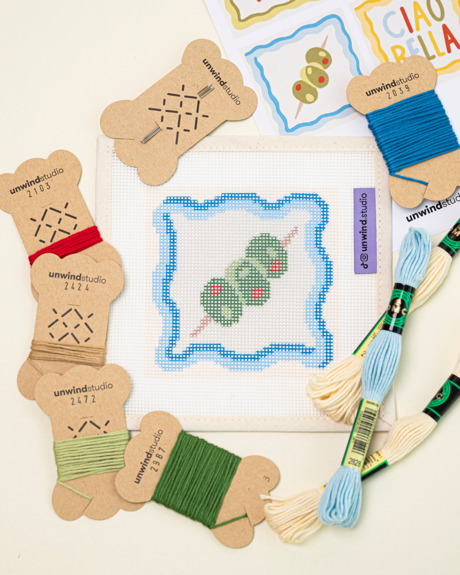 flat lay of the unwind studio dirty martini coaster with the matching DMC soft cotton threads and graphic flyer.