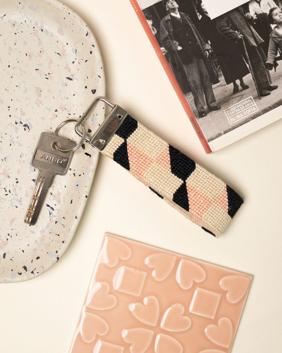 Echo Key Fob needlepoint kit place on a table with matching light pink decor elements and a book
