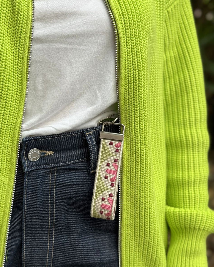Flourish Key fob with denim jeans and a bright green jacket
