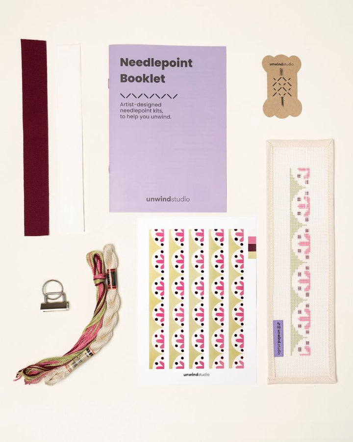 Flourish Complete Needlepoint Kit with finishing materials such as fusible web and cotton twill tape, key fob hardware plus matching threads, set of needles, a graphic flyer and a instructional booklet.