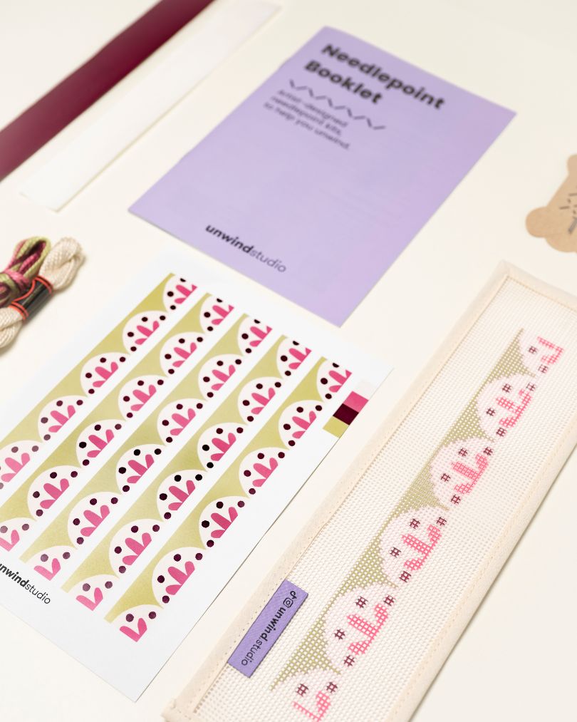 diagonal view of the Flourish Key Fob Needlepoint Kit with printed canvas, matching threads and finishing materials and a instructional booklet
