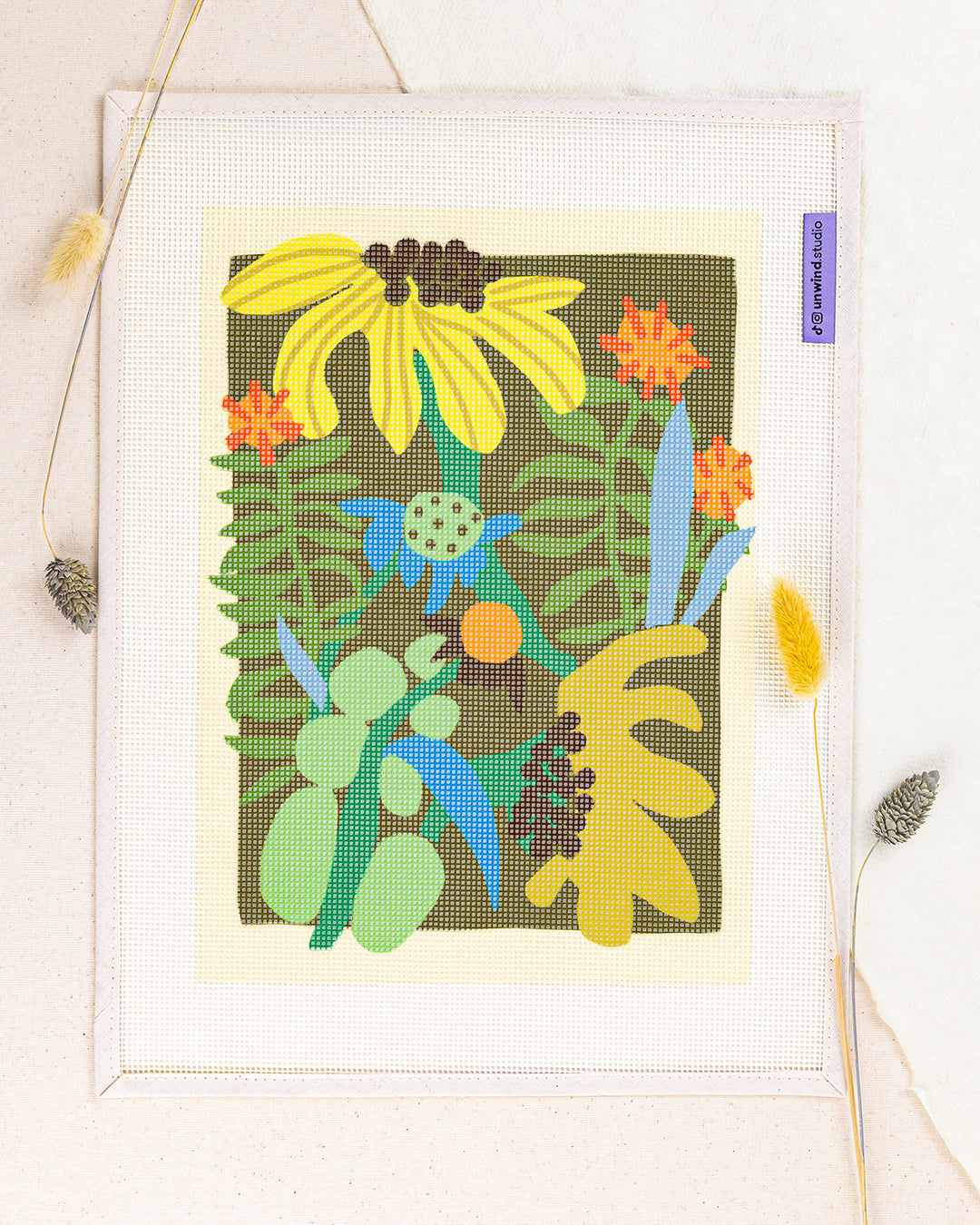 flower market needlepoint kit by Ophelia Pang: printed canvas of yellow flowers on green, framed with dried twigs
