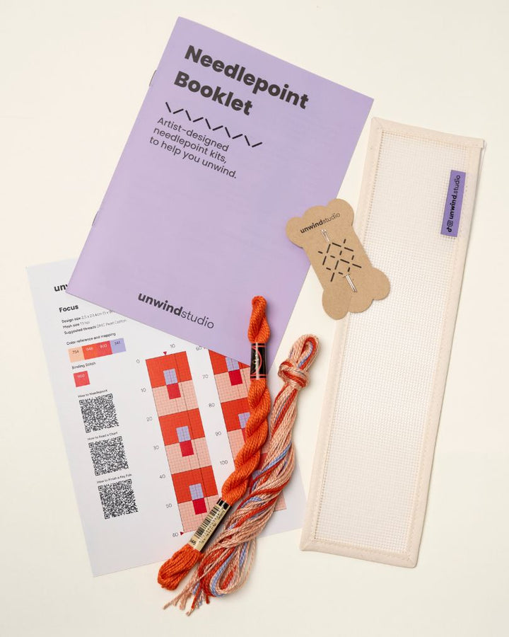 flat view of the Focus Key Fob Needlepoint Kit with blank canvas, matching threads, a instructional booklet and a graphic flyer
