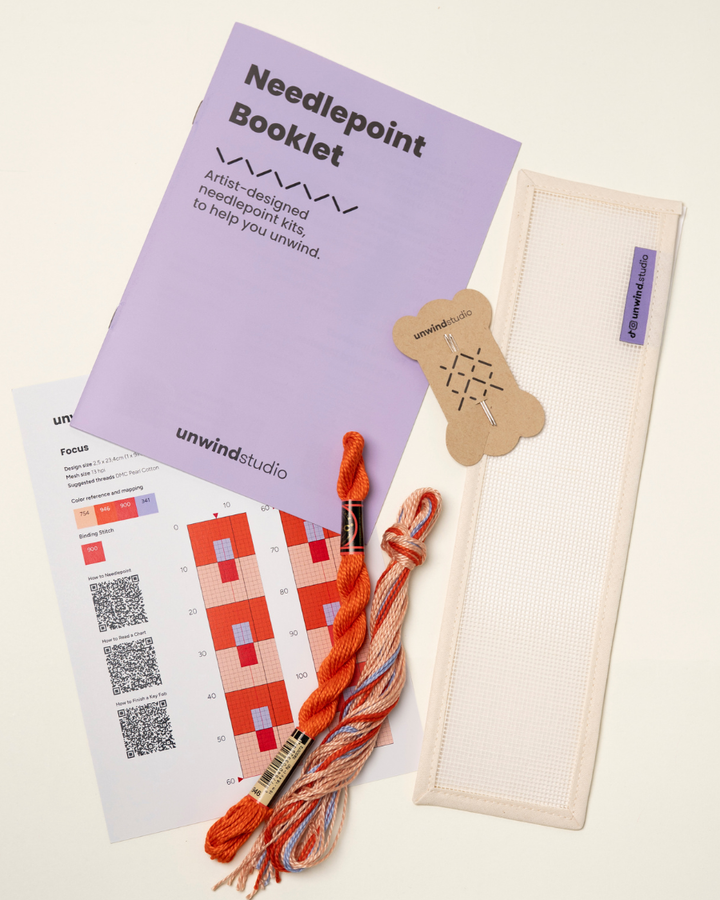 flat view of the Focus Key Fob Needlepoint Kit with blank canvas, matching threads, a instructional booklet and a graphic flyer