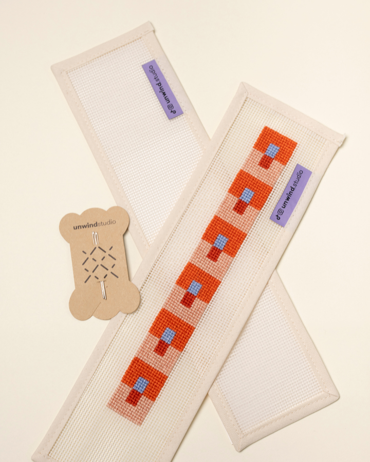 flat view of the Focus Key Fob Needlepoint Kit with blank canvas, a finished canvas and a pair of needles