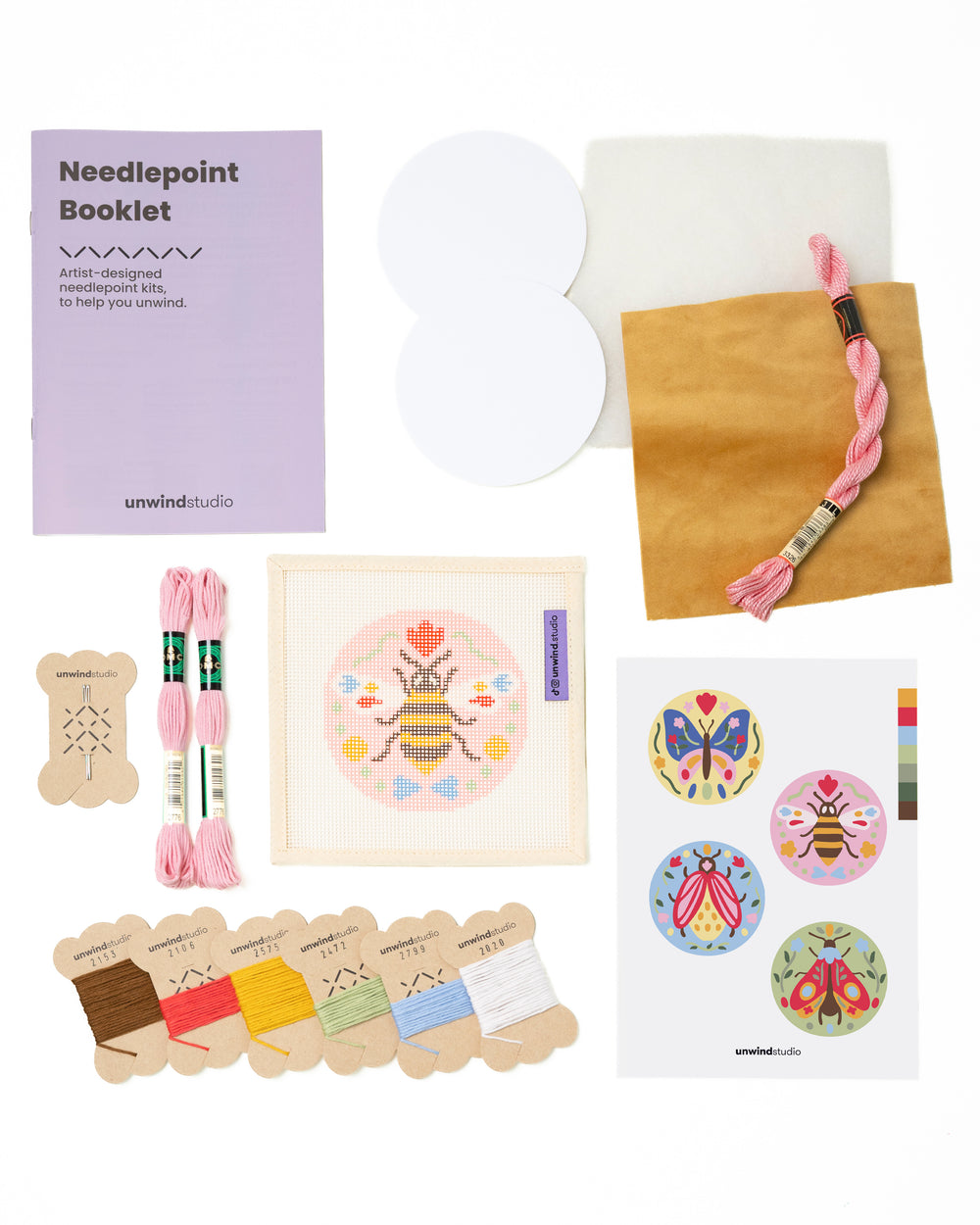 Flat view of the Folk Bee Needlepoint Ornament by Unwind Studio with everything that comes with the kit: an instructional booklet, needle, dmc soft cotton threads, finishing materials and a graphic flyer

