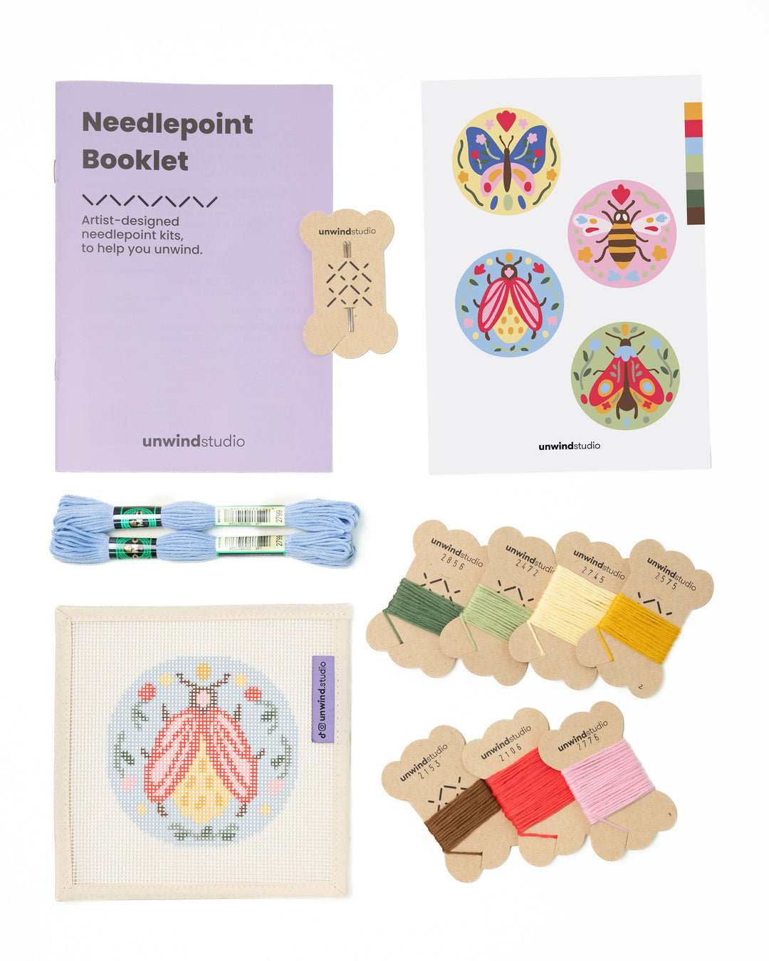 Flat view of the Folk Bee Needlepoint Ornament by Unwind Studio with an instructional booklet, needle, dmc soft cotton threads and a graphic flyer