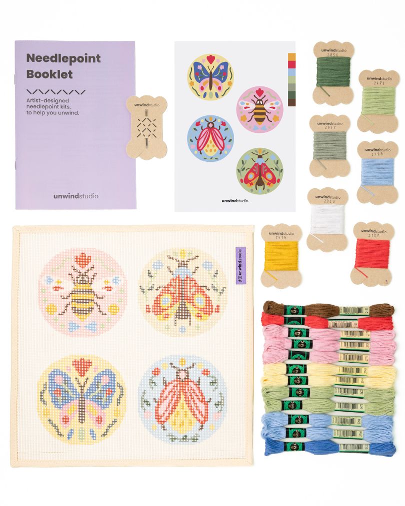 Flat view of the Folk Insect Needlepoint Ornament Set by Unwind Studio with an instructional booklet, needle, dmc soft cotton threads and a graphic flyer
