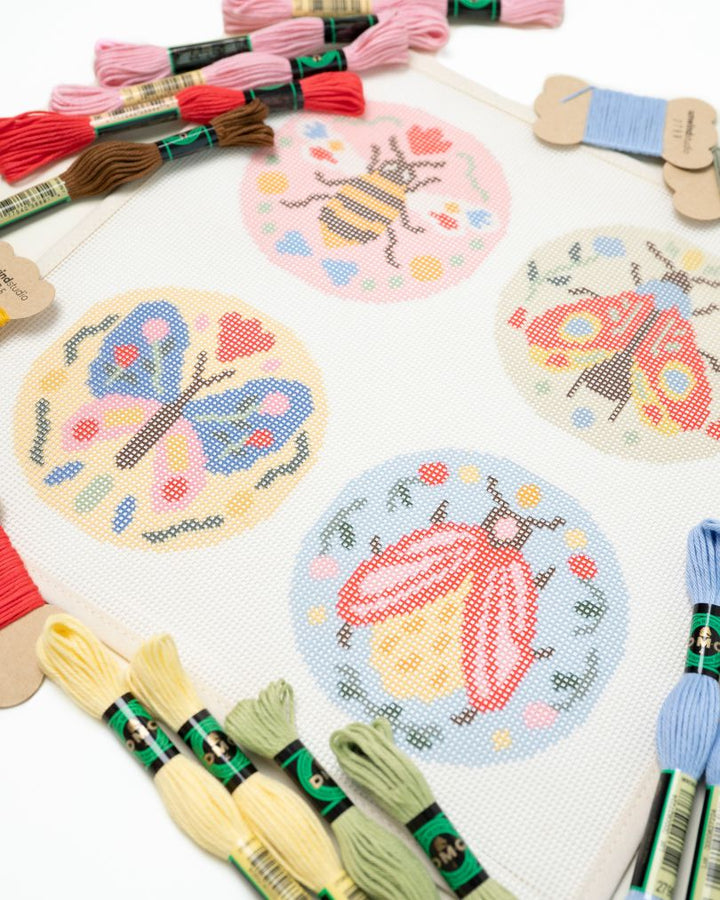 diagonal view of the Folk insects needlepoint set by unwinds studio with the matching DMC Perle cotton
