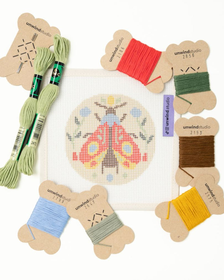 flat view of the folk moth needlepoint canvas with matching bold colored threads  
