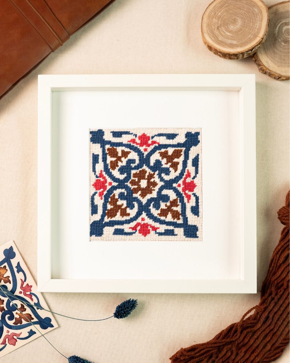Tile Foz Needlepoint Kit finished and framed next to earth tones decoration elements.