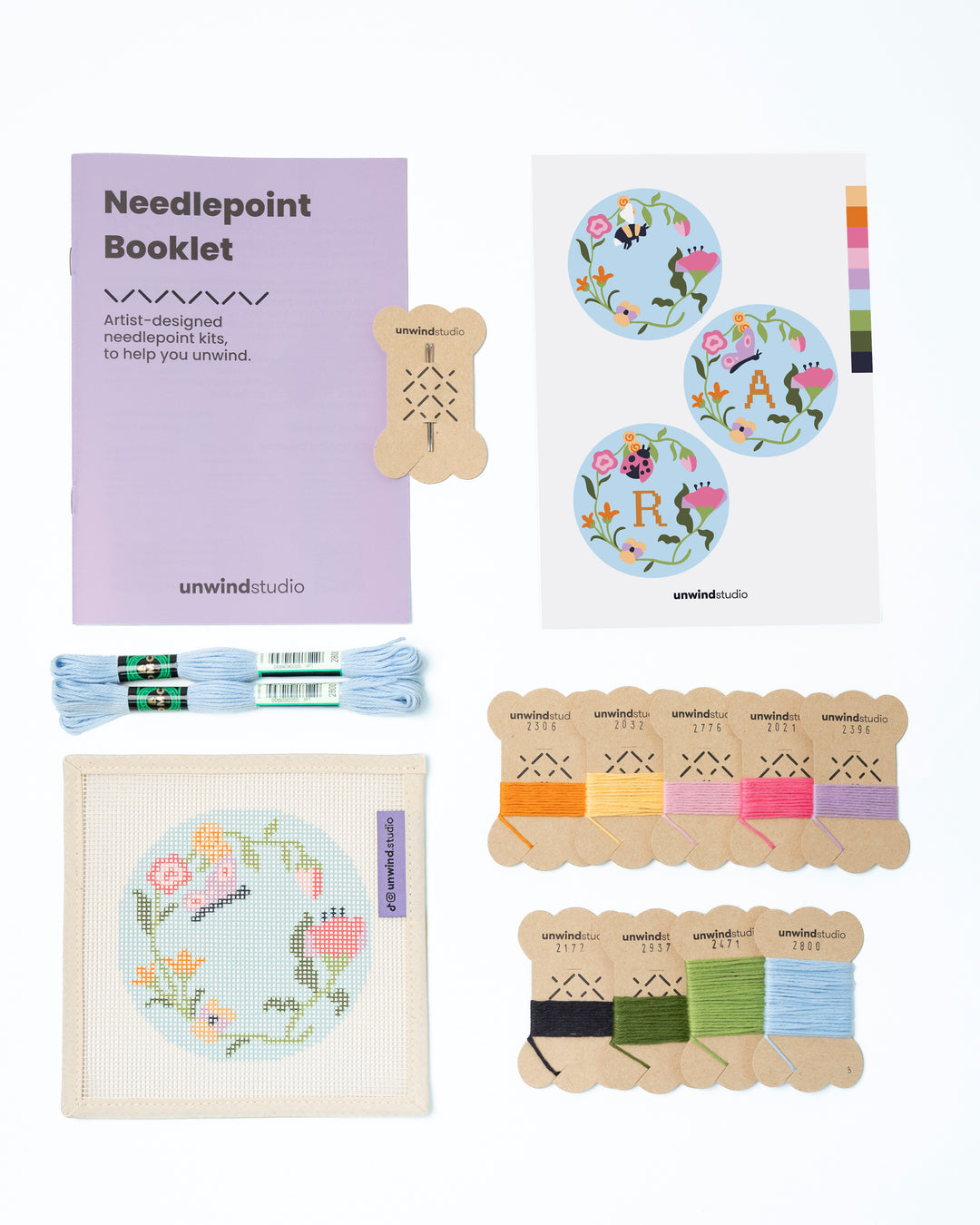 Flat view of the Garden Butterfly Needlepoint Ornament by Unwind Studio with an instructional booklet, needle, dmc soft cotton threads and a graphic flyer