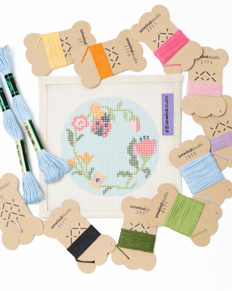 flat view of the Garden ladybug needlepoint canvas with matching bold colored threads  
