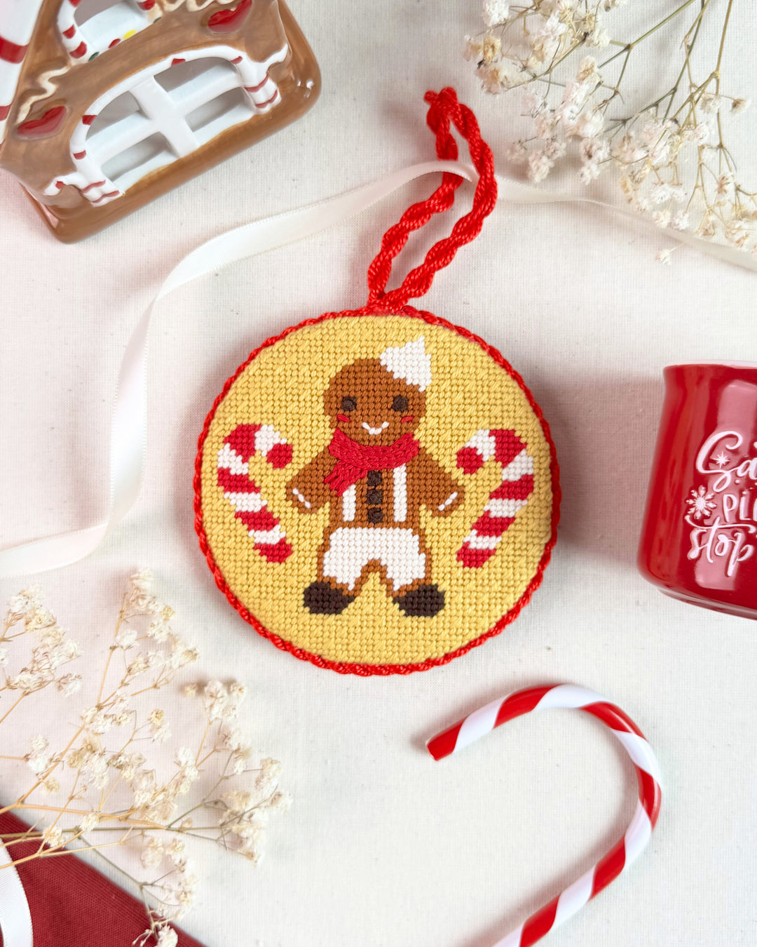 flat lay of the gingerbread boy needlepoint ornament kit finished and styled in a christmas setting