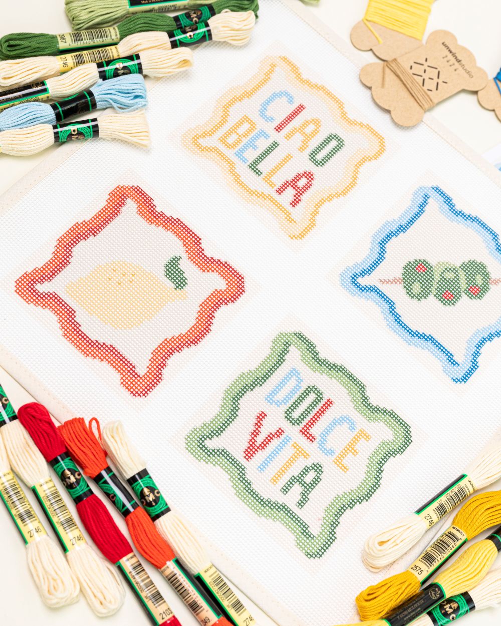 up-close shot of the unwind studio italian summer coaster set paired with the matching DMC Soft Cotton threads.