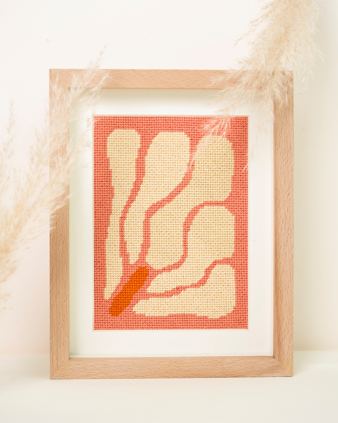 frontal shot of unwind studio itsas lorea needlepoint kit in a clean background wiht dry flowers.
