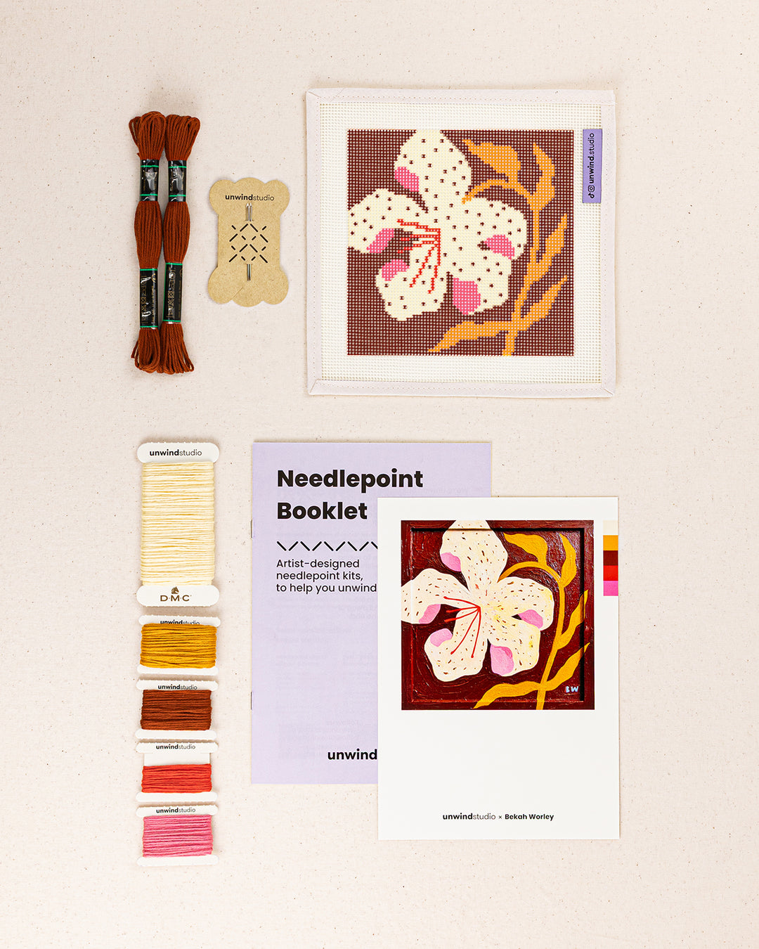 lily needlepoint kit contents: printed canvas, threads, needles, and instruction booklet, graphic flyer laid flat