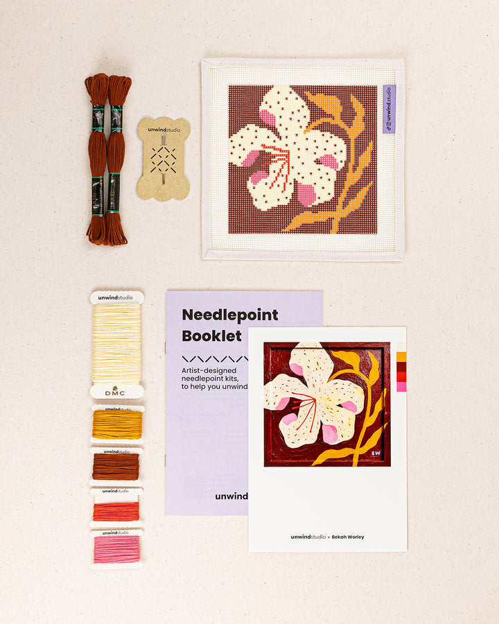 lily needlepoint kit contents: printed canvas, threads, needles, and instruction booklet, graphic flyer laid flat