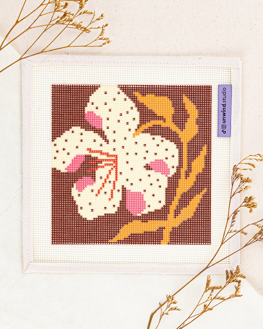 lily needlepoint kit by bekah worley: printed canvas of yellow flowers on blue, framed with dried twigs
