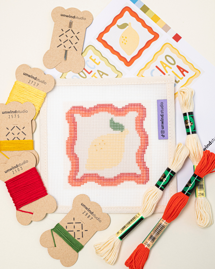 flat lay of the unwind studio limoncello spritz coaster with the matching DMC soft cotton threads and graphic flyer.