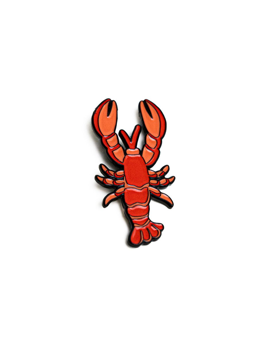 up-close shot of the unwind studio needle minder lobster magnet (enamel pin) in a bold red and orange color.