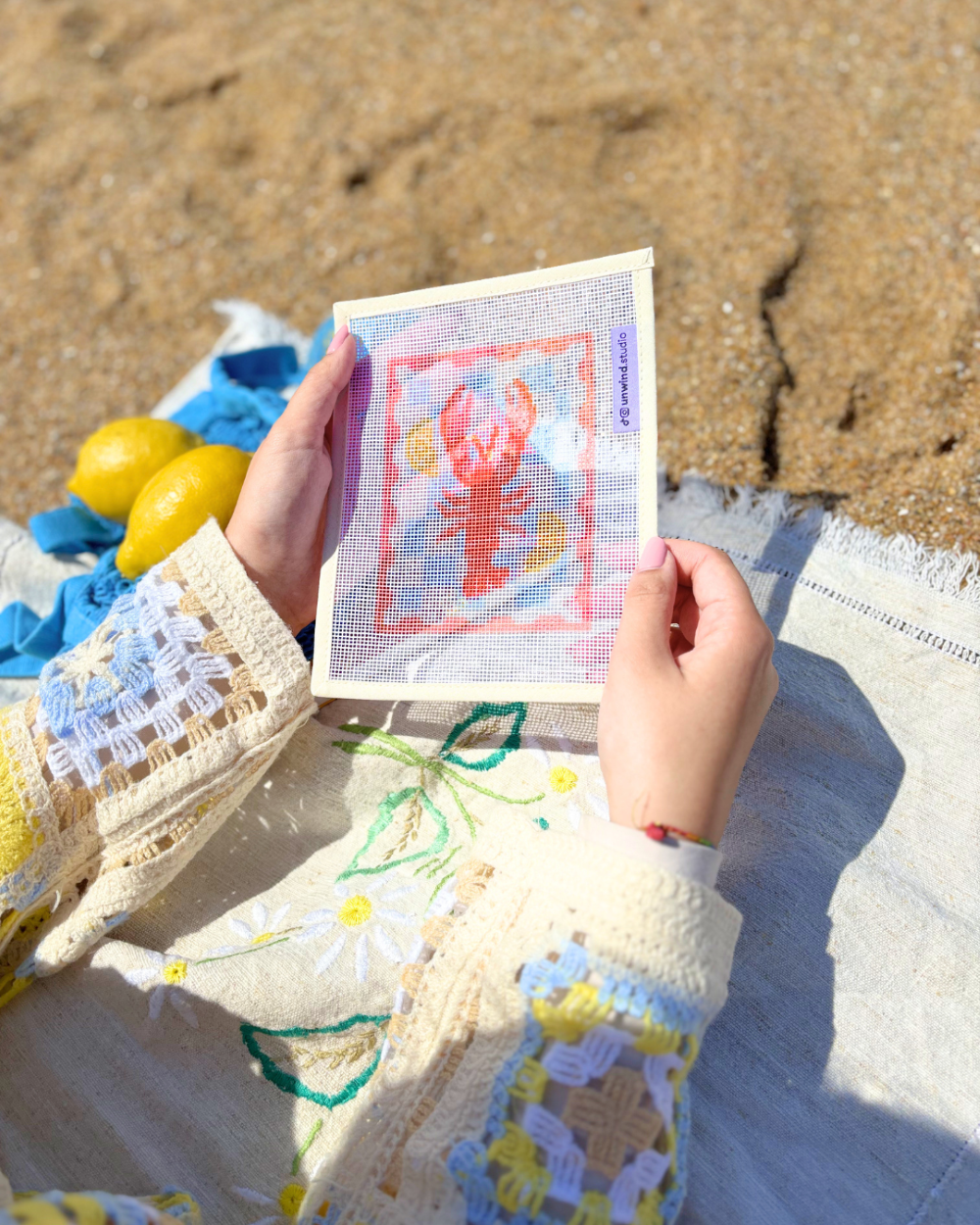 close-up look at unwind studio Lobster Stamp being held on a beach towel.