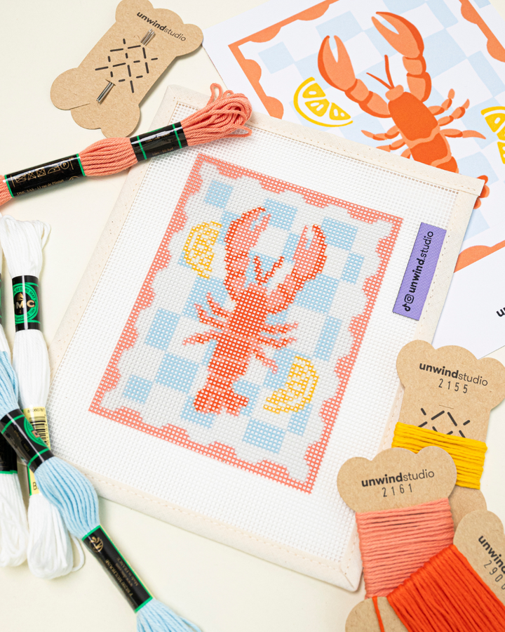 close-up diagonal shot of the unwind studio lobster stamp paired with matching DMC soft cotton threads.