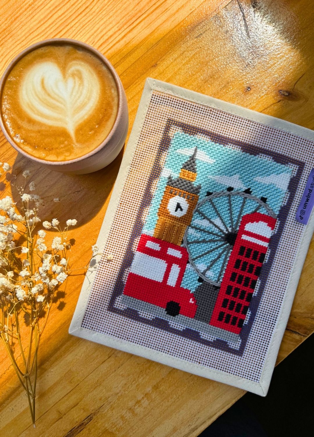 finished London Stamp/Postcard set in a wooden table, with a aesthetic latte and a set of dry flowers